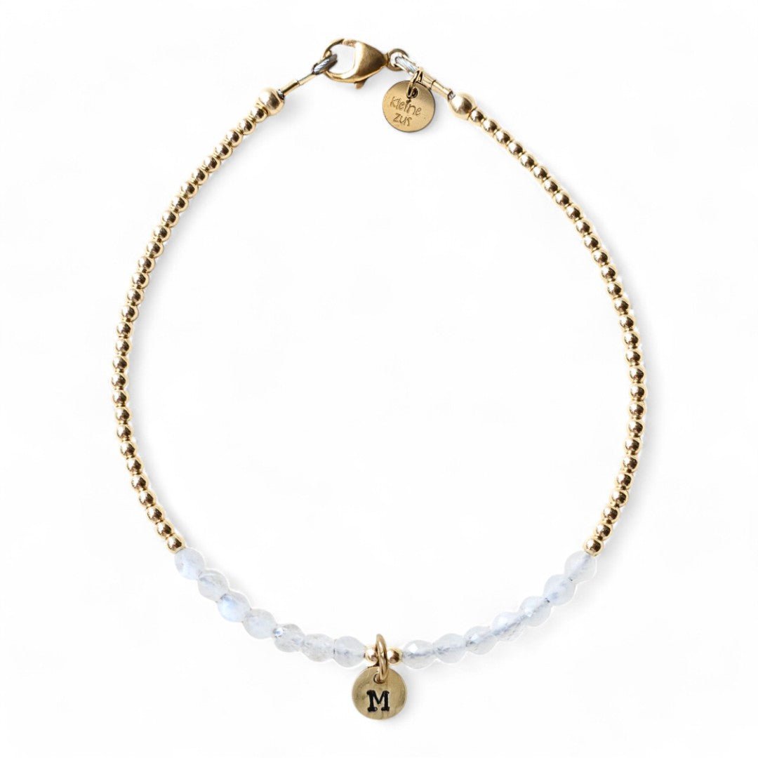 Gouden dames armband Maaike met 2mm gouden kraaltjes gecombineerd met maansteen, in het midden van het armbandje hangt een gouden initiaalbedeltje van 6mm
