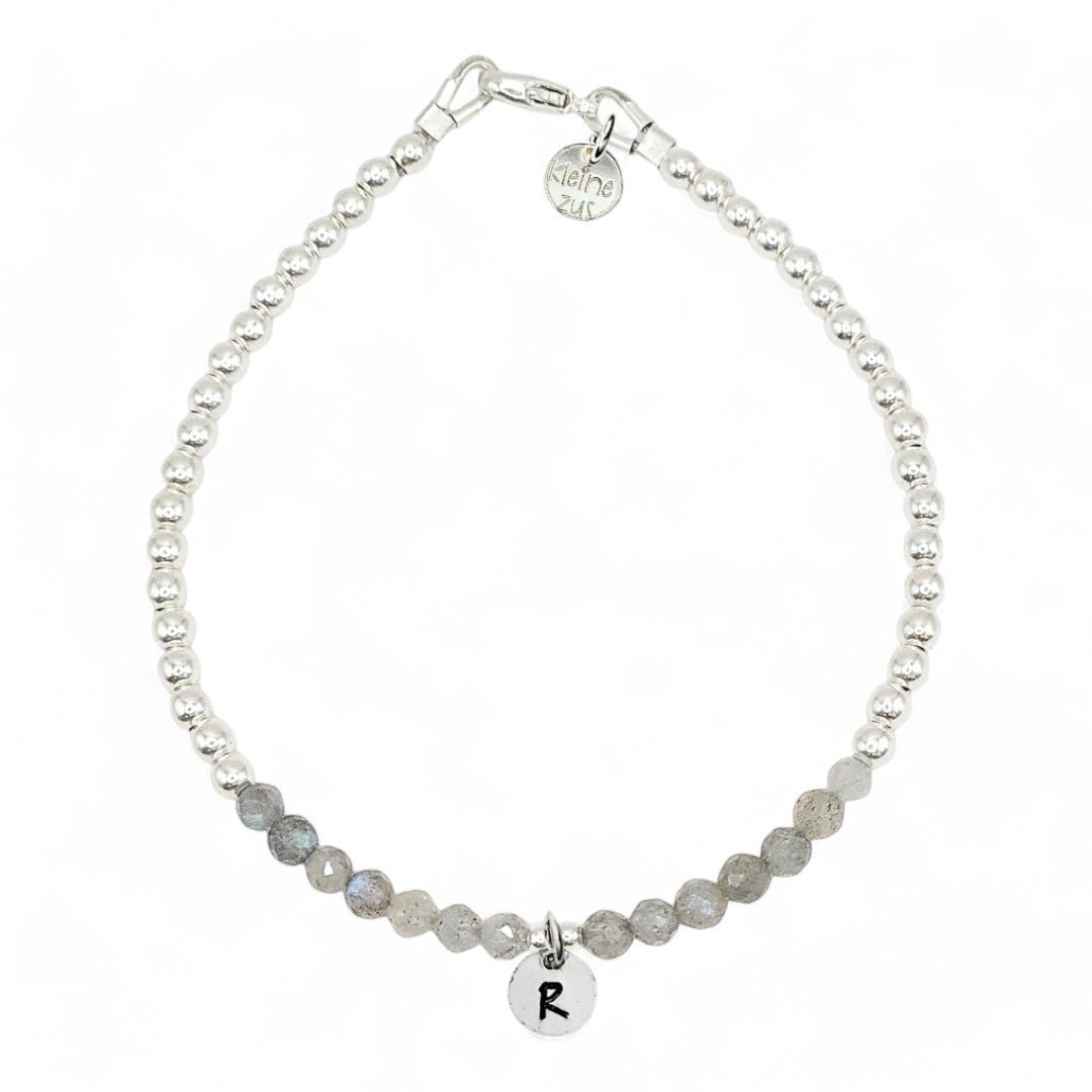 Zilveren dames armband Pien met 3mm zilveren kraaltjes gecombineerd met labradoriet , in het midden hangt een zilveren initiaalbedeltje van 6mm