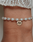 Armband met naam dames goud Luna.
Parels gecombineerd met 2mm gouden kralen. Aan de armband hangt een gouden 10mm naambedel