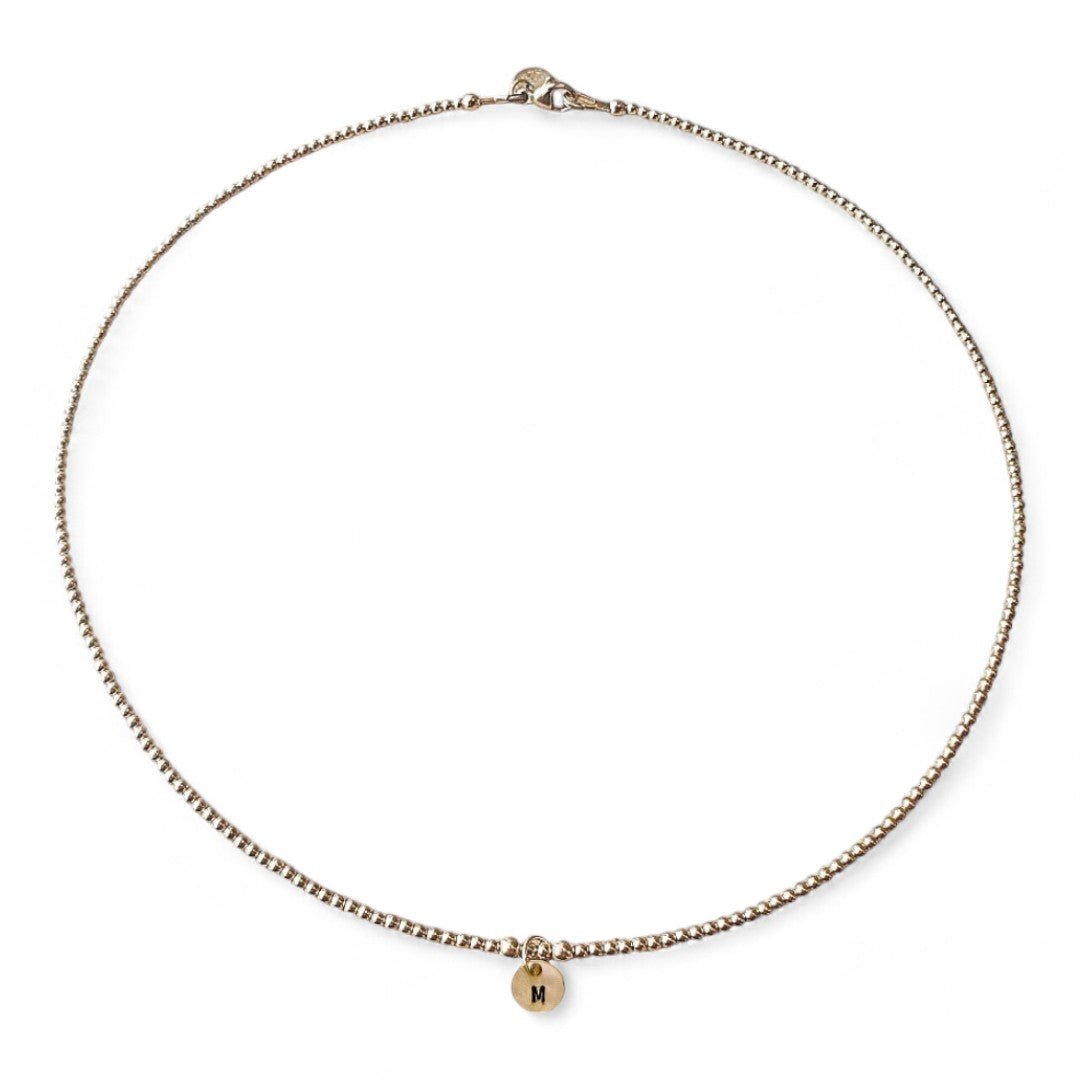 Gouden dames ketting met 2mm kralen, in het midden hangt een 6mm letterbedel