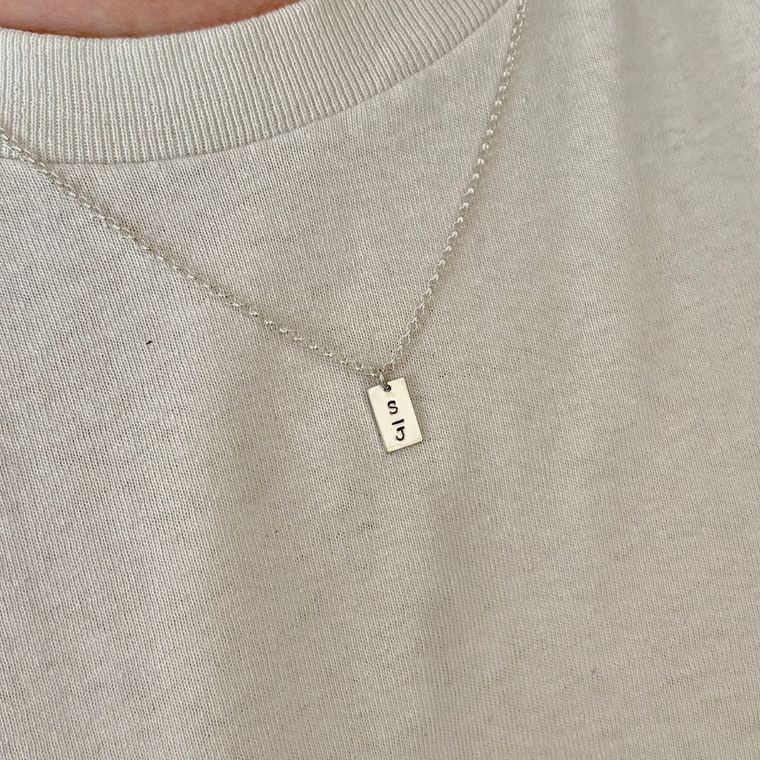 Zilveren ketting , aan de ketting hangt een zilveren tag waar letters op gestempeld kunnen worden