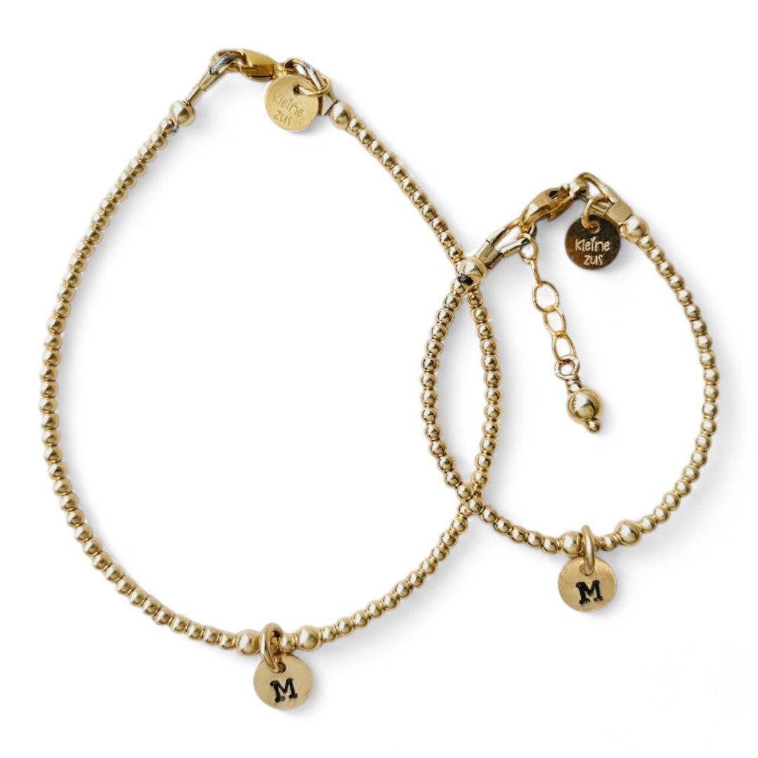 Moeder dochter armband goud Lieve met 2mm kraaltjes, in het midden hangt een gouden initiaalbedeltje van 6mm