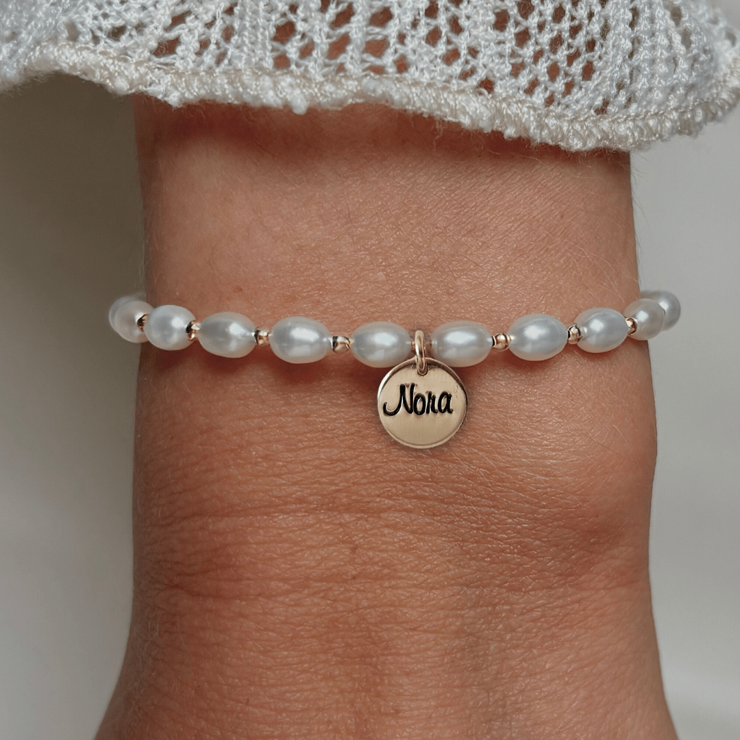 Armband met naam dames goud Luna.
Parels gecombineerd met 2mm gouden kralen. Aan de armband hangt een gouden 10mm naambedel