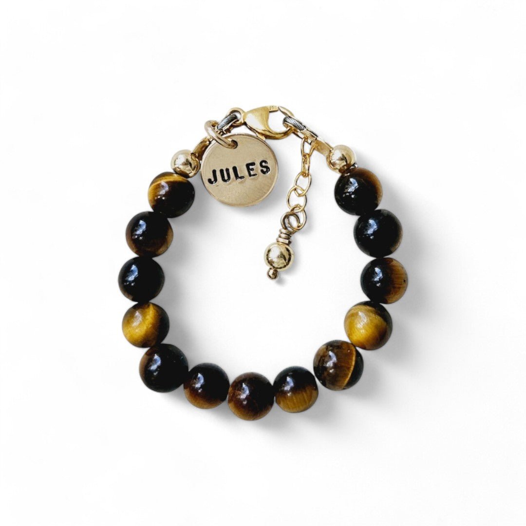 Gouden jongens armbandje Ian is gemaakt van 6mm natuursteenkralen tijgeroog, aan de sluiting hangt een gouden naambedel van 10mm