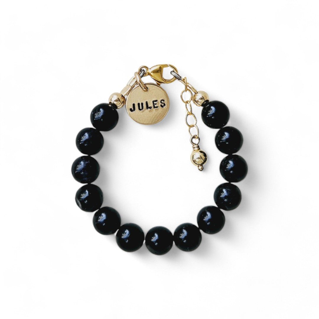 Gouden jongens armbandje Joeri is gemaakt van 6mm natuursteenkralen Obsidiaan, aan de sluiting hangt een gouden naambedel van 10mm