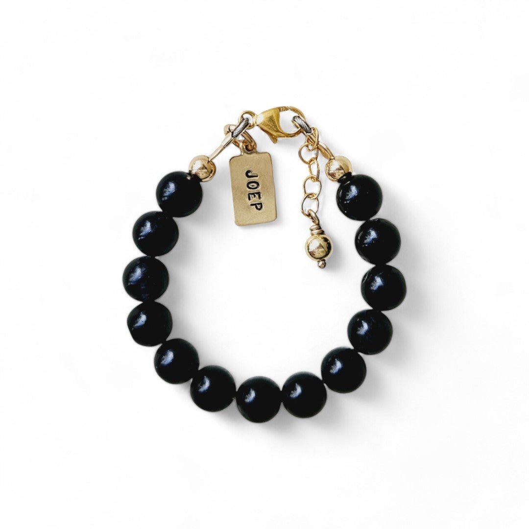 Gouden jongens armbandje Joeri is gemaakt van 6mm natuursteenkralen Obsidiaan, aan de sluiting hangt een gouden naambedel