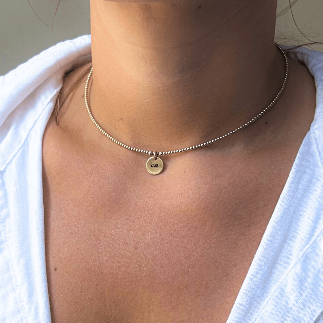 Gouden dames ketting met naam, de ketting is gemaakt van 2mm kralen, in het midden van de ketting hangt een naambedel van 10mm