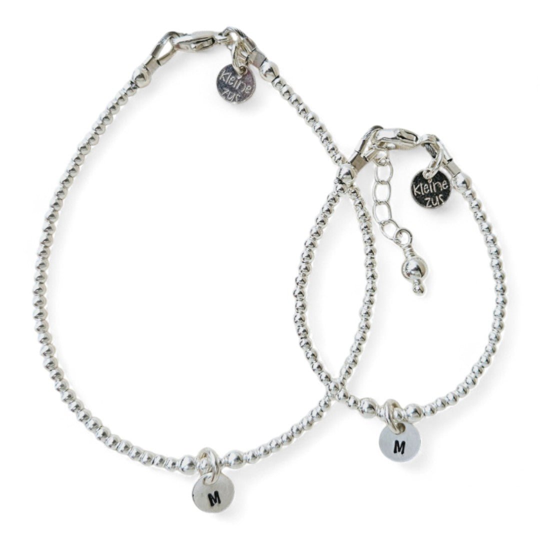 Moeder dochter armband zilver Lieve met 2mm kraaltjes, in het midden hangt een zilveren initiaalbedel van 6mm